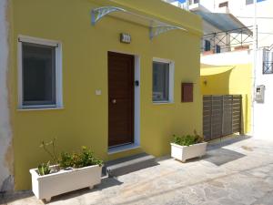 a yellow house with two plants in front of it at Nisos suite in Ermoupoli