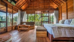 a bedroom with a bed and a table and windows at Anja Villas Ubud in Tegalalang +59 photos