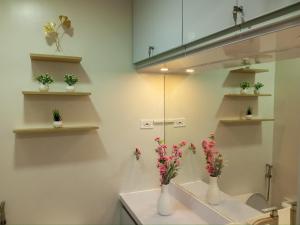 Un baño con dos jarrones blancos con flores. en Osam Empire Suites 2BR Staycation at Trees Residences Condominium, en Manila