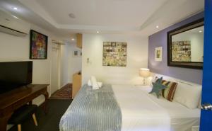 a bedroom with a large bed and a television at Hideaway Noosa Men Only Beach Resort in Peregian Beach