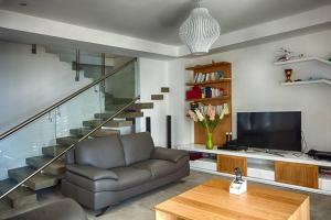 un soggiorno con divano, TV e scale di Villa luxueuse - Pointe aux Sables a Pointe aux Sable