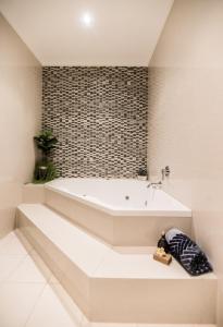 a white bath tub in a bathroom with a brick wall at Lakeview luxury apartment in The Entrance
