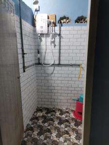 ein Bad mit einer weiß gefliesten Dusche mit einem Schlauch in der Unterkunft Homestay Kenangan Kemaman in Cukai