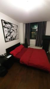 sypialnia z czerwonym łóżkiem i oknem w obiekcie Double Room with Shared Bathroom w Londynie
