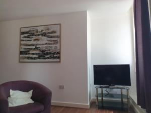 a living room with a chair and a television at Double Room with Shared Bathroom in London