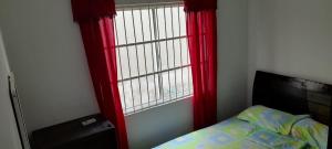 a bedroom with red curtains and a bed and a window at Apartamento Don Mathias # 1 in Coveñas