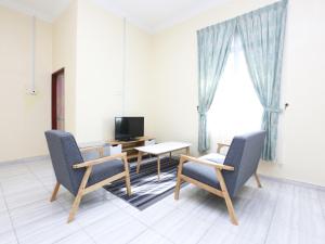 sala de estar con 2 sillas, mesa y TV en Aloha Chalet en Kampung Raja