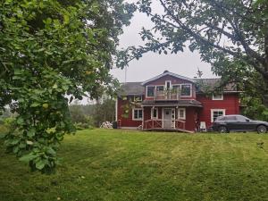 a red house with a car parked in front of it at Embracing nature's Swedish house in Ludvika