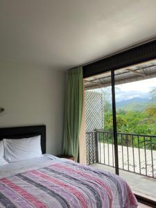 a bedroom with a bed and a large window at The Sandy House Khaolak in Khao Lak