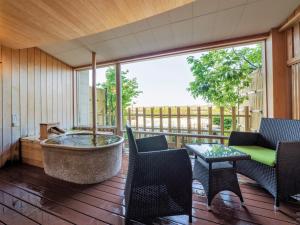 - une terrasse couverte avec une baignoire, des chaises et une table dans l'établissement Awara Onsen Matuya Sen Sen, à Awara