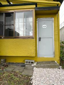 żółty dom z białymi drzwiami i oknem w obiekcie NewOpen FreeParkingOtaru小樽湾一望ハウスOkanoue House戸建 w mieście Otaru