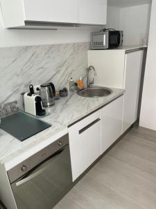 a white kitchen with a sink and a microwave at Grand studio neuf à 50 m du port in Saint-Tropez +28 photos