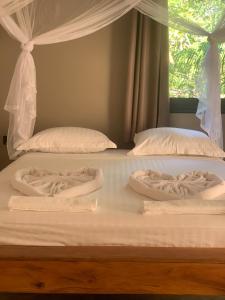 two white beds with white sheets and a window at MAISON CARREE in Andilana