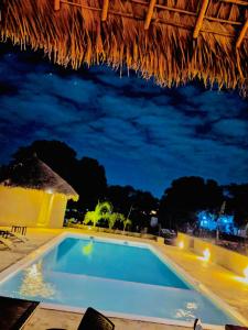 uma piscina à noite com um telhado de palha em MAISON CARREE em Andilana