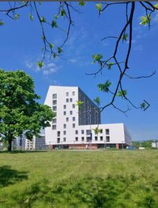 ein großes weißes Gebäude auf einem Feld mit einem Baum in der Unterkunft 3 izbový apartmán hneď pri letisku, možnosť rezervovať parking in Prievoz