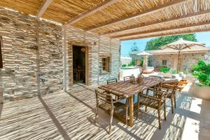 a patio with a wooden table and chairs and a stone wall at Kyparissi Country House in Marmaroto
