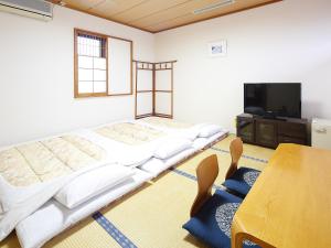 a room with two beds and a table and a tv at Yokaichi Royal Hotel in Yōkaichi