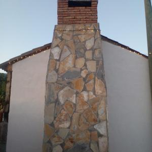 a building with a stone wall and a brick tower at Casa en el corazón de San Antonio de las Alazanas in San Antonio de las Alzanas
