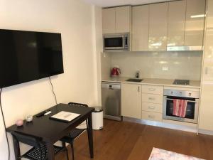 a small kitchen with a table and a television at Lovely refurbished 1 bed near marina + parking in Sydney