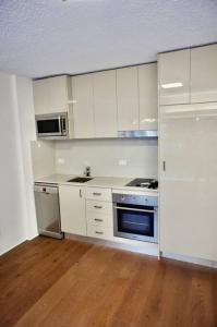 a kitchen with white cabinets and a stove top oven at Lovely refurbished 1 bed near marina + parking in Sydney