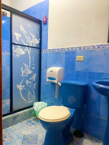 a blue bathroom with a toilet and a sink at Hostal Vista al Mar in Puerto Baquerizo Moreno