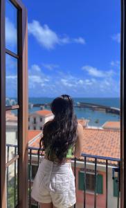 Una mujer mirando por una ventana al océano en Sunset Hotel Phu Quoc - welcome to a mixing world of friends en Phu Quoc