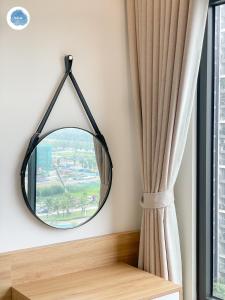 un miroir rond suspendu sur un mur à côté d'une fenêtre dans l'établissement It Dust Homestay 2 - The Wooden Apartment, à Hanoï