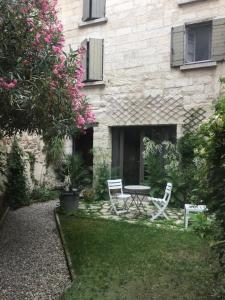 een tuin met twee stoelen en een tafel voor een gebouw bij Petite maison sur jardin secret in Avignon