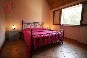 a bedroom with a bed with a red bedspread and a window at La Cupa - Torre Vado in Torre Vado
