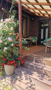a wooden porch with flowers and a table and chairs at Dierewnia-chata blisko Białowieży in Kojły