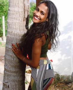 a woman is standing next to a tree at Amanda Beach Resort in Pasikuda