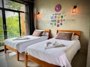 2 Betten in einem Zimmer mit Fenster in der Unterkunft The Sunnery Ville in Lom Kao