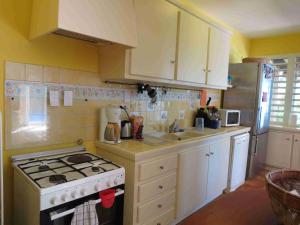 a kitchen with white cabinets and a stove top oven at Villa Bourbon avec piscine sur la plage in Saint-Gilles les Bains
