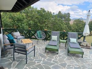 eine Gruppe Stühle und ein Sonnenschirm auf einer Terrasse in der Unterkunft Casa Mila Zlatibor in Zlatibor