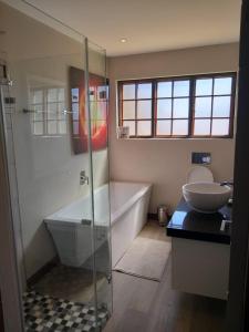 a bathroom with a shower and a tub and a sink at Kliphuisjes in Dullstroom