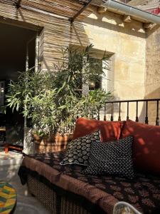 um sofá com almofadas numa varanda com plantas em La Maison de Fabienne em Tarascon