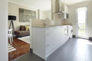 cocina con electrodomésticos blancos y sala de estar. en Duke by FeelFree Rentals, en San Sebastián