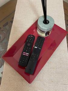 two remote controls sitting on top of a red table at Homestay Haris nearby USIM in Nilai