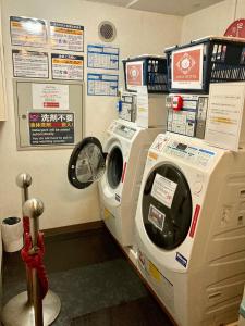 a washing machine in a room with signs on the wall at Apoa Hotel in Yokkaichi