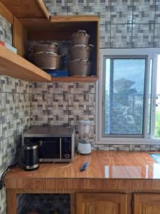 eine Küchentheke mit einer Mikrowelle und einem Fenster in der Unterkunft Chez Roland in Kribi