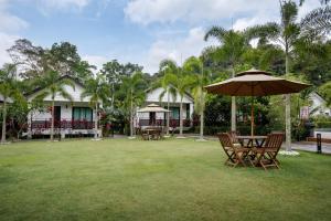 uma mesa e cadeiras com um guarda-sol num quintal em Villa Renai Resort em Bentong