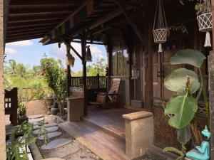 une terrasse couverte d'une maison avec une chaise et des plantes dans l'établissement Ogek Home Stay, à Ubud