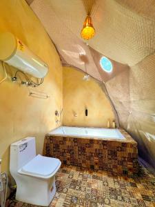 a bathroom with a toilet and a bath tub at Whoopers Boutique Resort Jibhi in Jibhi
