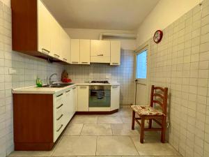 una cucina con armadi bianchi, lavandino e sedia di Vespucci 8 a Castro di Lecce
