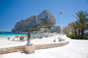 una playa con sombrillas y el océano y una montaña en Villa Inia - PlusHolidays, en Calpe