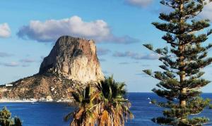 a mountain in the ocean with a palm tree at Villa Inia - PlusHolidays in Calpe
