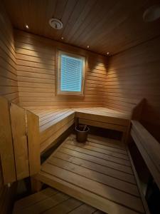 a wooden sauna with a window and a bucket in it at Lumikukka Vuokatti in Kajaani