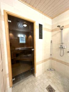 a bathroom with a shower and a glass door at Lumikukka Vuokatti in Kajaani