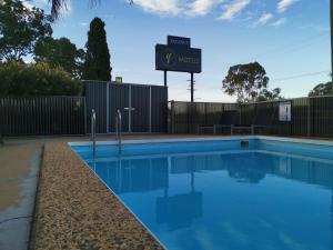 une piscine avec un panneau à côté d'une clôture dans l'établissement Y Motels Kingaroy, à Kingaroy