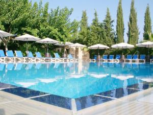 una gran piscina con sillas y sombrillas en Apollonia Hotel Apartments, en Pafos